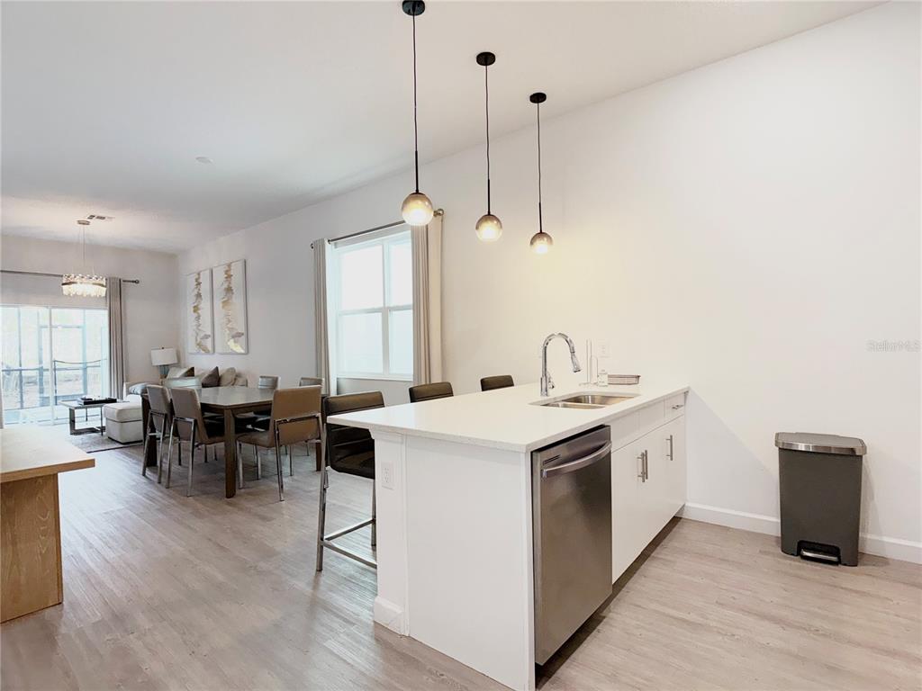 A kitchen island with a stainless steel dishwasher sits in an open-concept living space — 332 FAMAGUSTA DRIVE, DAVENPORT, FL