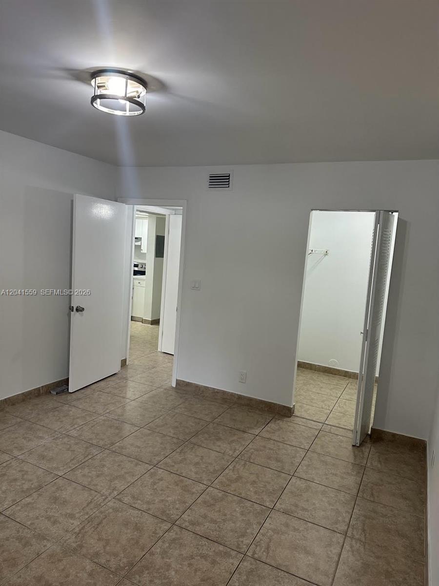 A room with tiled floors, a ceiling light fixture, a doorway, and a walk-in closet — 8100 Geneva Ct # 142, Doral FL 33166, DORAL, FL