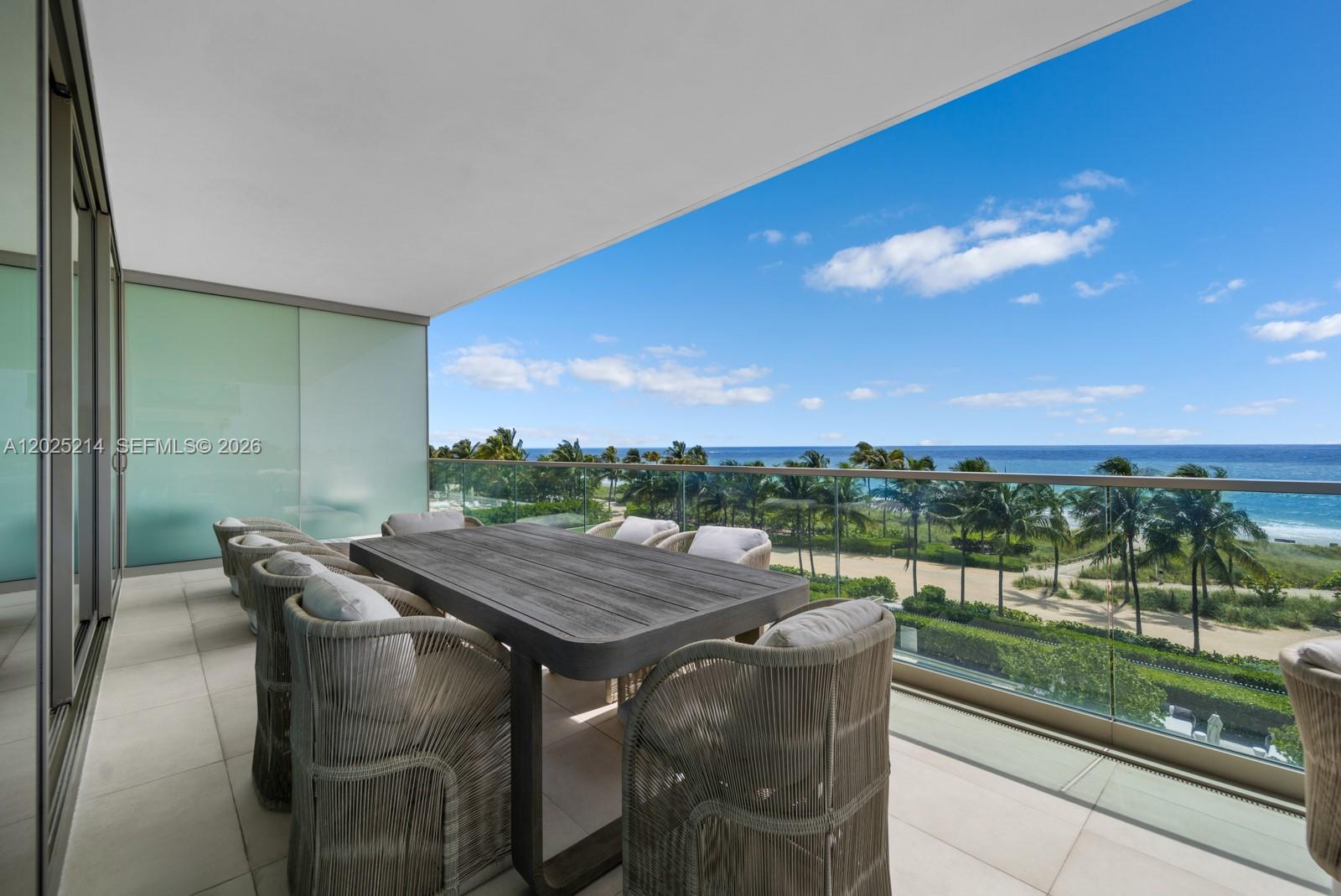 A balcony with a dining table and chairs overlooks a beach and the ocean — 10203 Collins Ave # 403, Bal Harbour FL 33154, BAL HARBOUR, FL