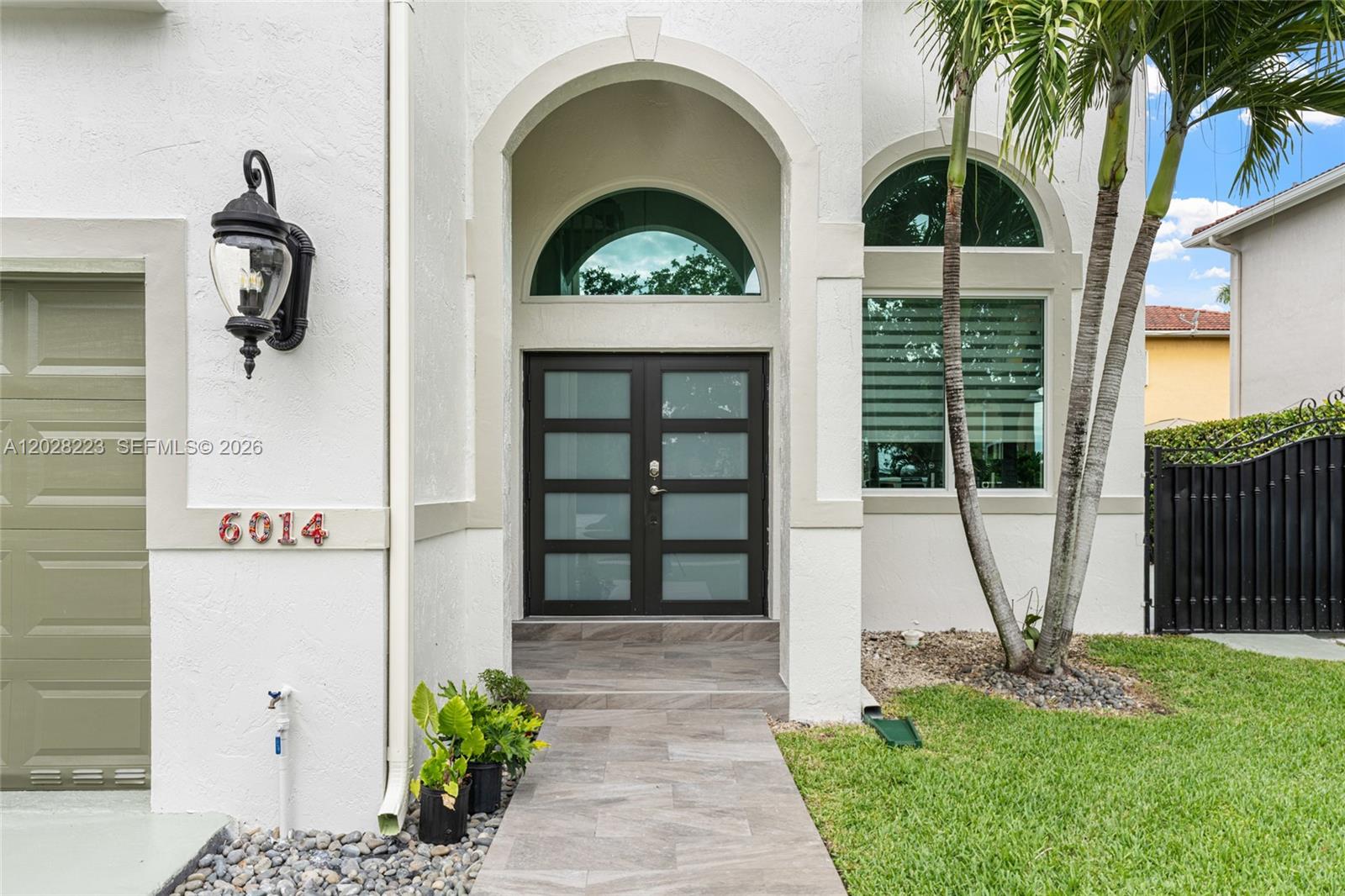 The exterior of a white house features a double front door and an arched window — 6014 SW 160th Ave, Miami FL 33193, MIAMI, FL