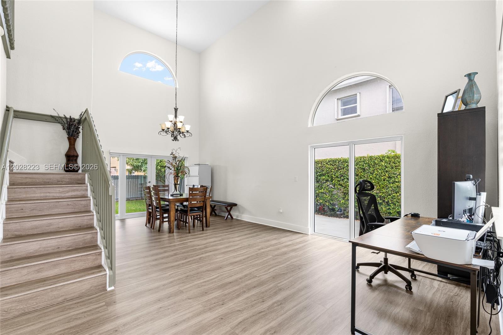 This open-concept room features high ceilings, wood-look flooring, a dining area, and a home office — 6014 SW 160th Ave, Miami FL 33193, MIAMI, FL