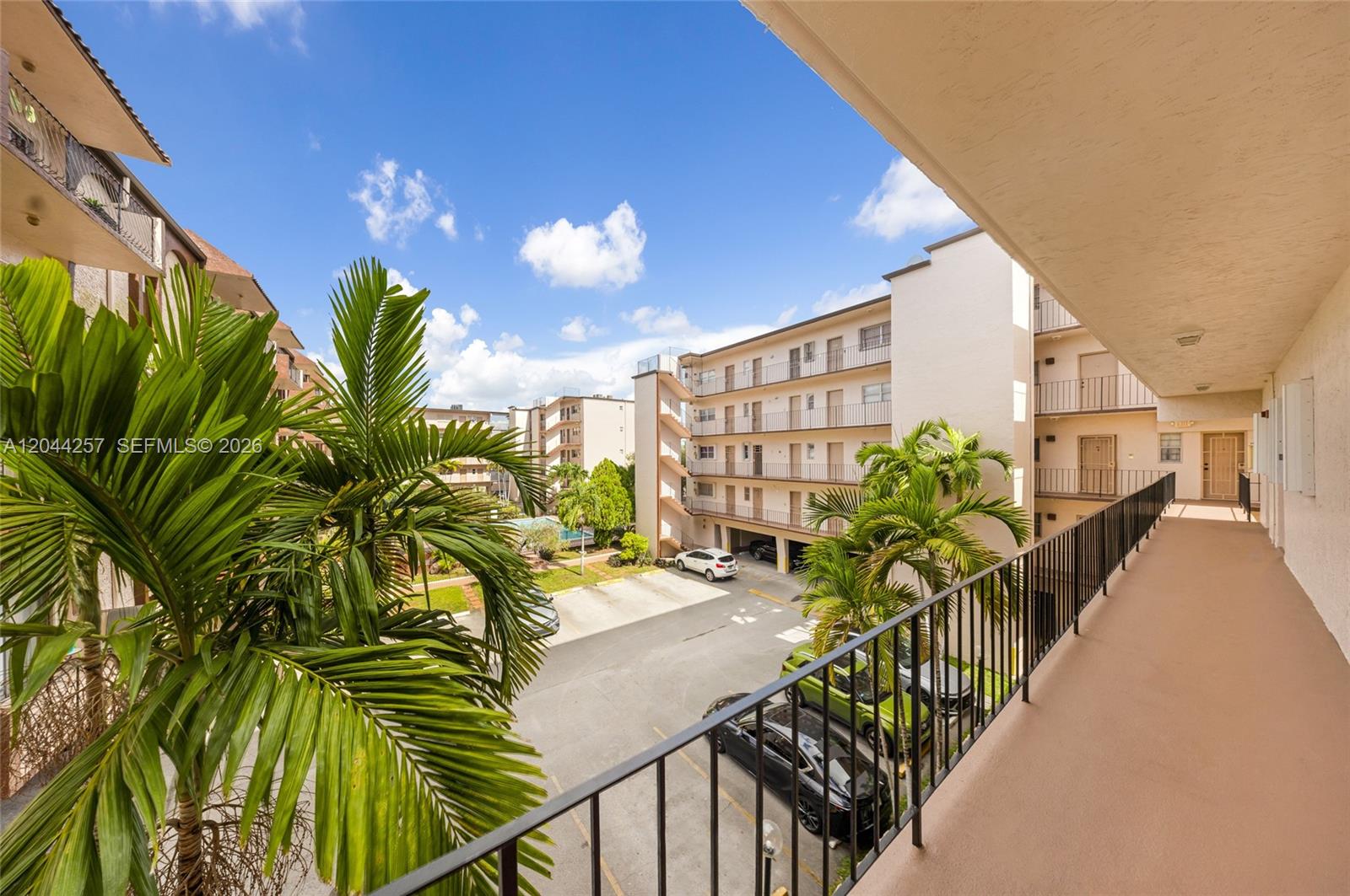 An elevated view from a balcony overlooking a parking lot and apartment complex buildings — 1950 W 54th St # 206, Hialeah FL 33012, HIALEAH, FL