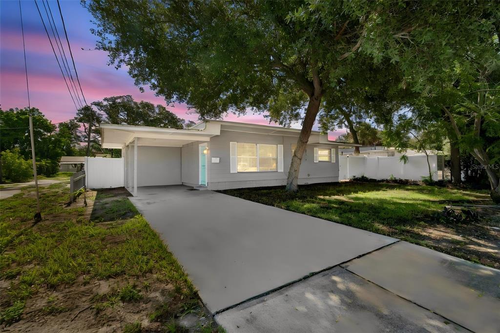 A single-story house with a gray exterior, a carport, and a concrete driveway at sunset — 516 64TH STREET S, ST PETERSBURG, FL