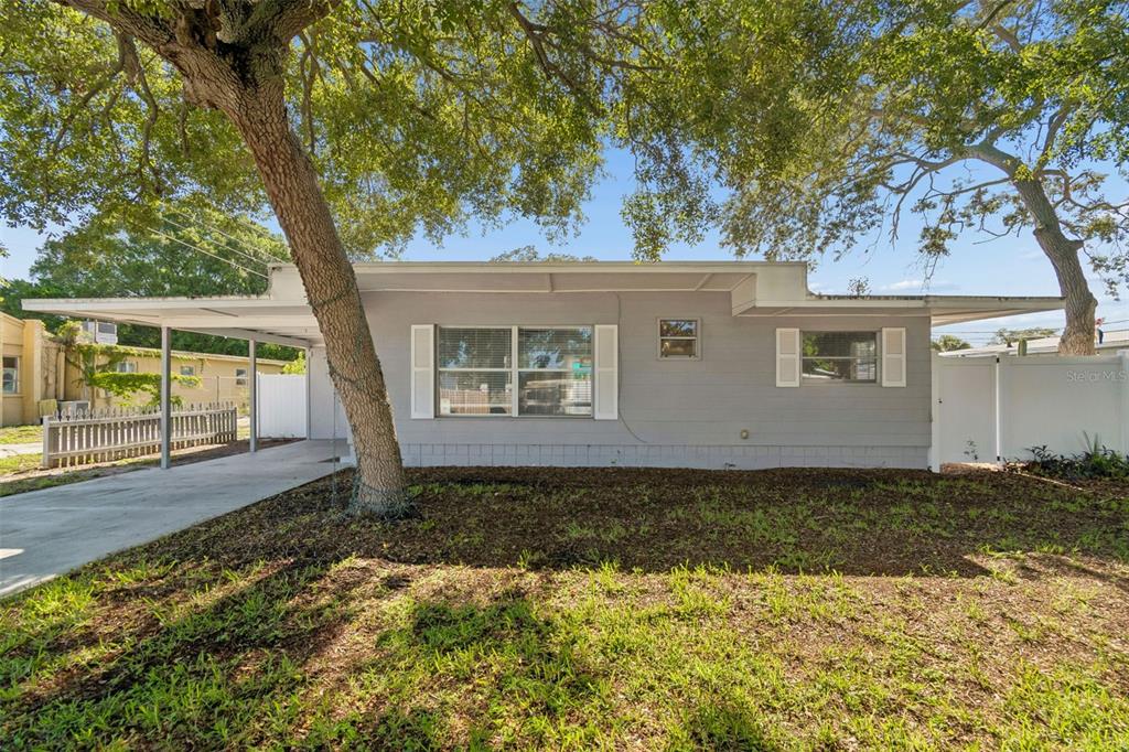 A single-story gray house with a carport and a large tree in the front yard — 516 64TH STREET S, ST PETERSBURG, FL