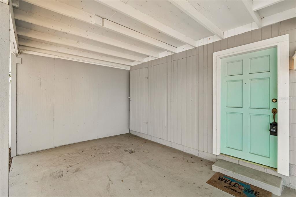 A covered entryway features gray vertical siding, a concrete floor, and a light blue door — 516 64TH STREET S, ST PETERSBURG, FL