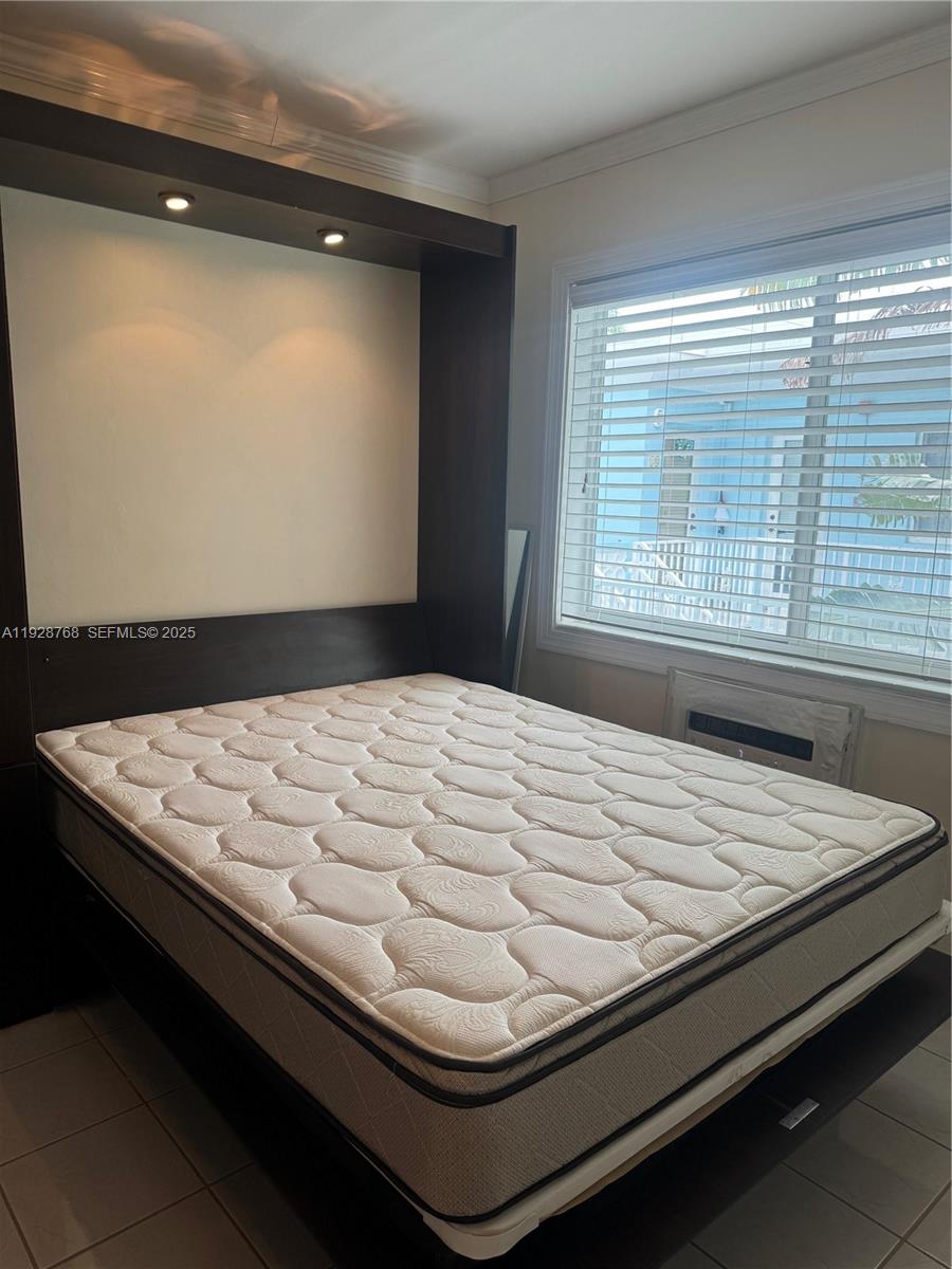A bedroom features a dark wood Murphy bed with built-in lighting and a window — 401 Collins Ave # 21, Miami Beach FL 33139, MIAMI BEACH, FL