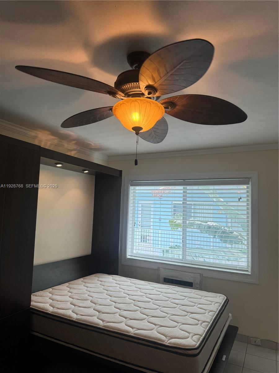 A bedroom features a palm-leaf ceiling fan, a mattress on a dark frame, and a window — 401 Collins Ave # 21, Miami Beach FL 33139, MIAMI BEACH, FL