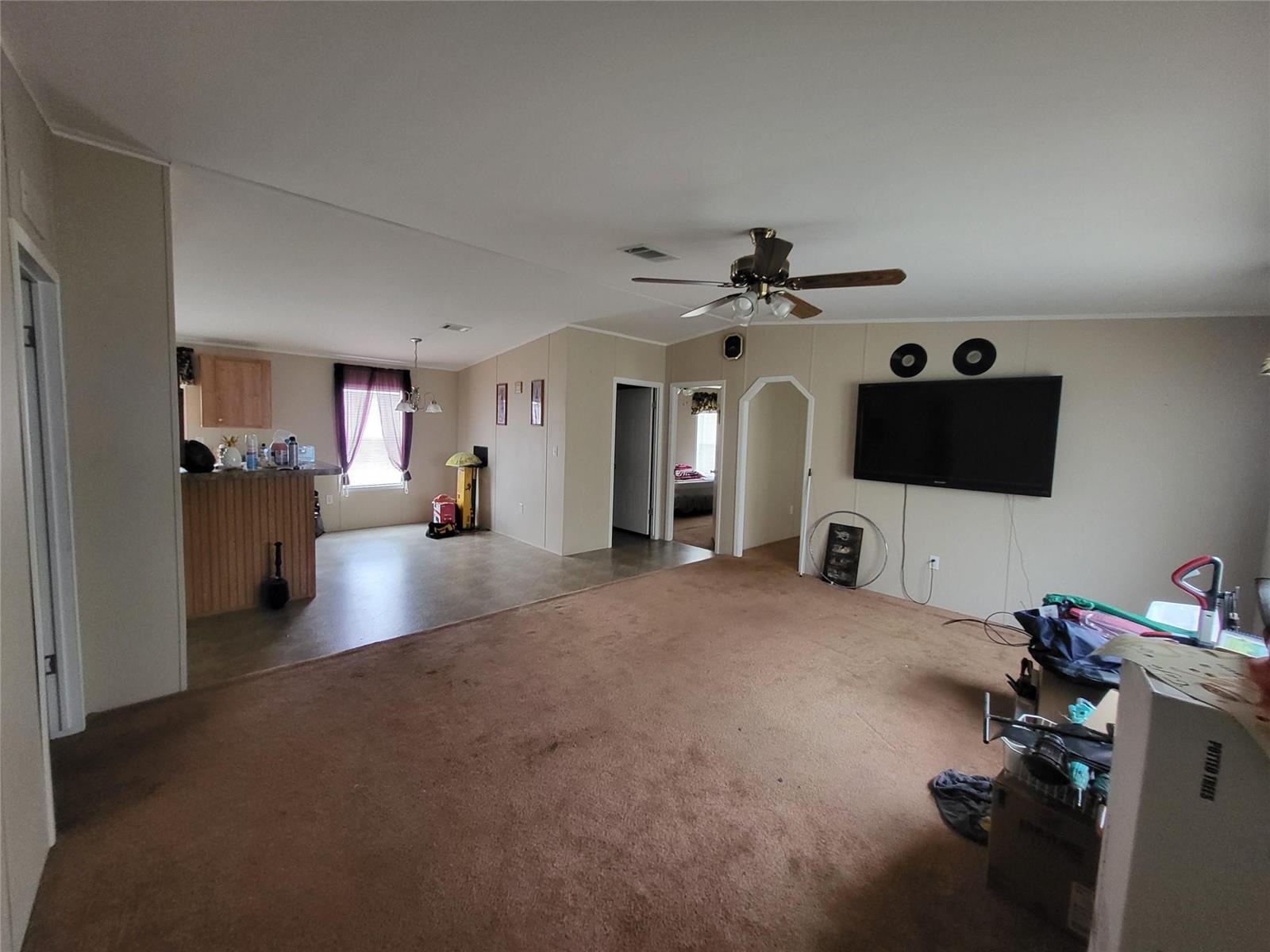 A living room with brown carpet, a ceiling fan, and a wall-mounted television — 1057 Blue Heron, Moore Haven FL 33471, MOORE HAVEN, FL