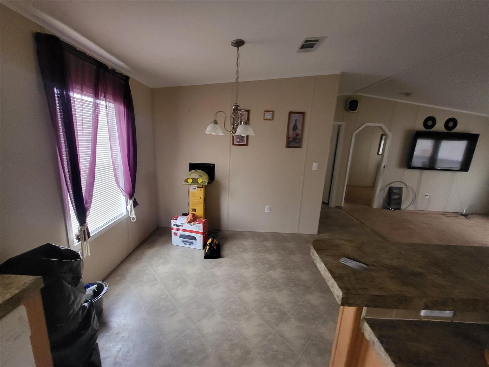 A dining area features a chandelier, vinyl flooring, and a window with purple curtains — 1057 Blue Heron, Moore Haven FL 33471, MOORE HAVEN, FL