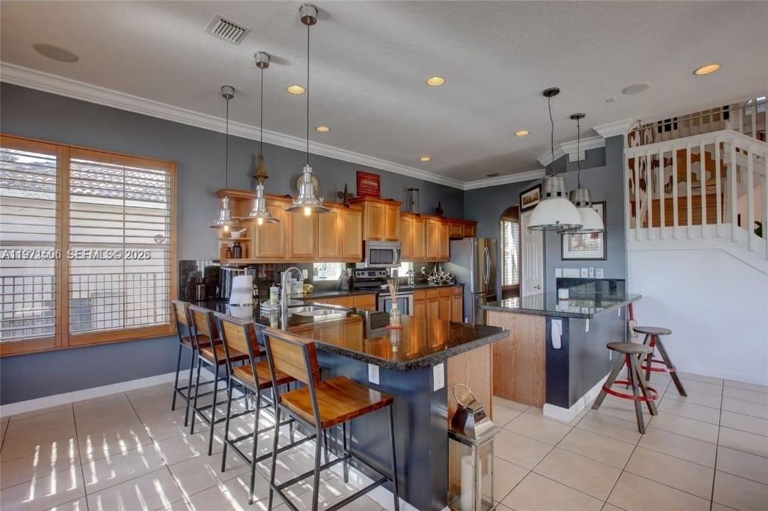 A kitchen features wood cabinets, dark granite countertops, a breakfast bar, and tile flooring — 2789 SW 130th Ter, Miramar FL 33027, MIRAMAR, FL