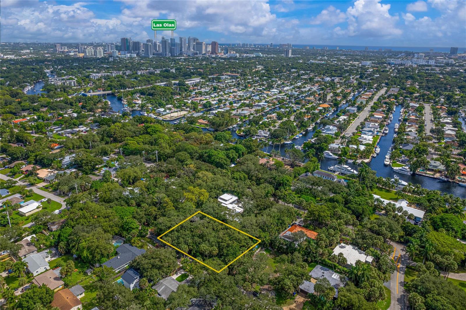 An aerial view shows a rectangular vacant lot surrounded by dense trees and residential homes — FORT LAUDERDALE, FL