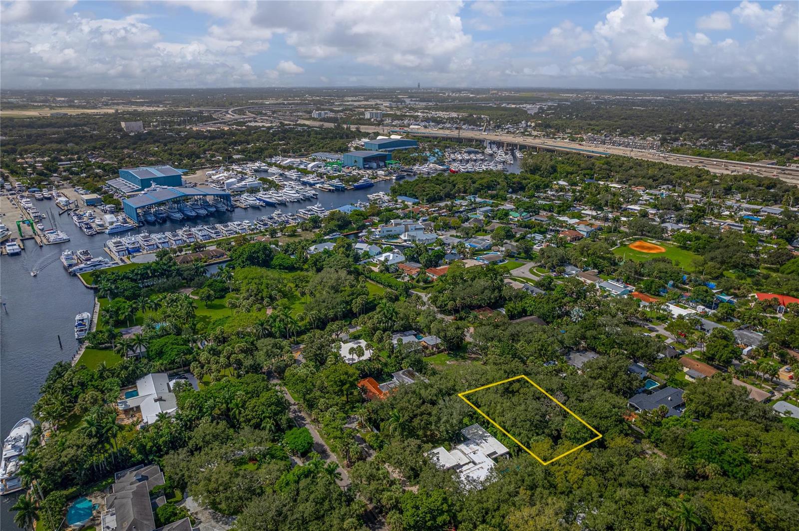 An aerial view shows a wooded residential lot outlined in yellow near a boat marina — FORT LAUDERDALE, FL