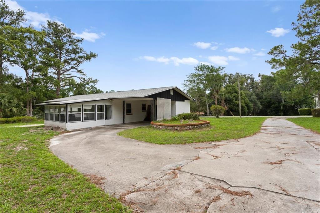 A single-story house with a screened porch and attached carport sits on a large lot — 23363 NW 191ST AVENUE, HIGH SPRINGS, FL