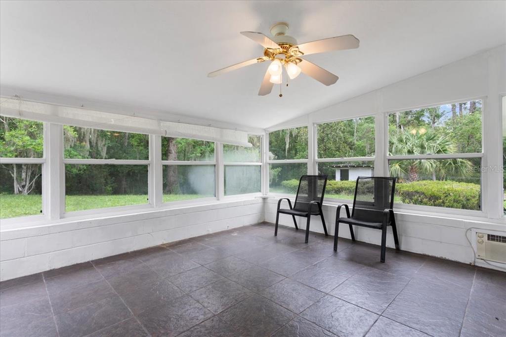 A sunroom with dark tile flooring, a ceiling fan, and large windows overlooking a yard — 23363 NW 191ST AVENUE, HIGH SPRINGS, FL