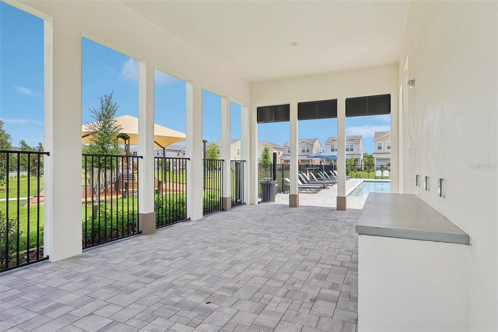 A covered patio features paver flooring, a built-in counter, and views of a pool area — 1813 LATTICE WAY, ST CLOUD, FL