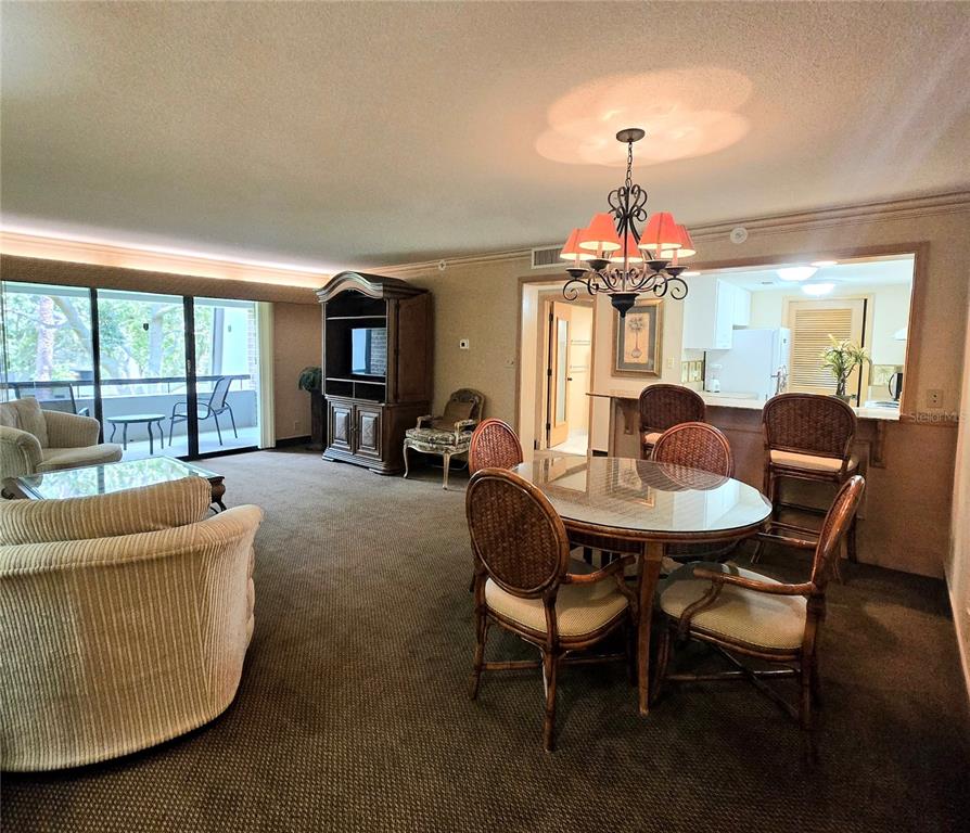 A dining area with a glass-topped table and wicker chairs sits before an open kitchen — 36750 US HIGHWAY 19 N UNIT 15-219, PALM HARBOR, FL