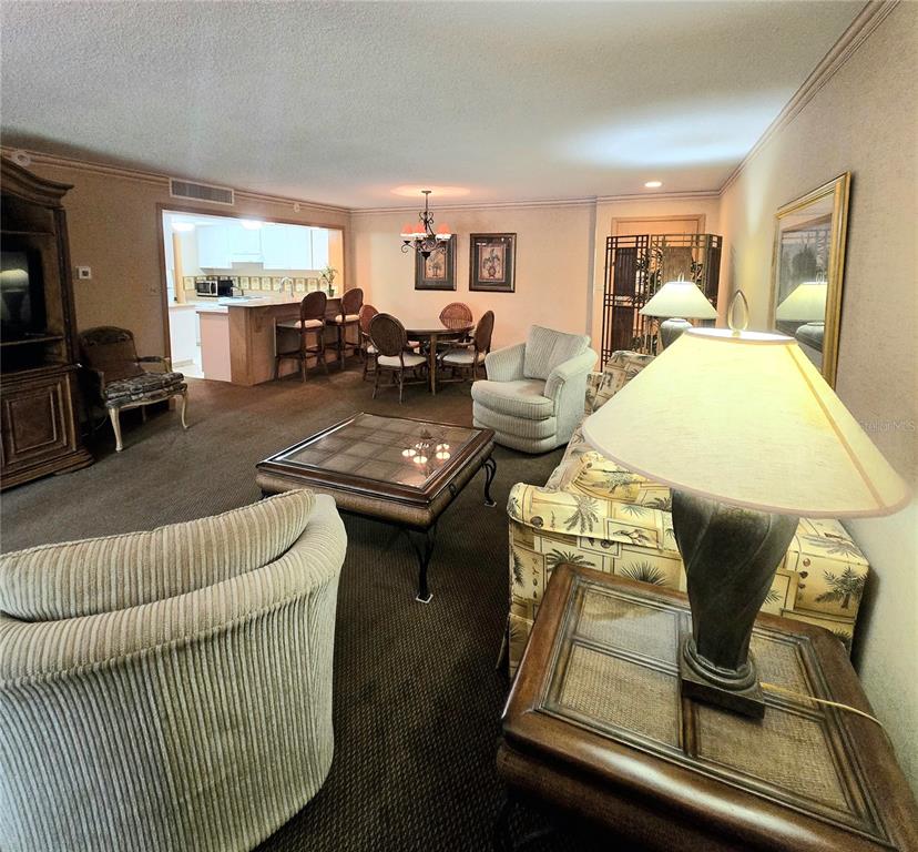 A living room and dining area feature brown carpeting, a glass-topped coffee table, and furniture — 36750 US HIGHWAY 19 N UNIT 15-219, PALM HARBOR, FL