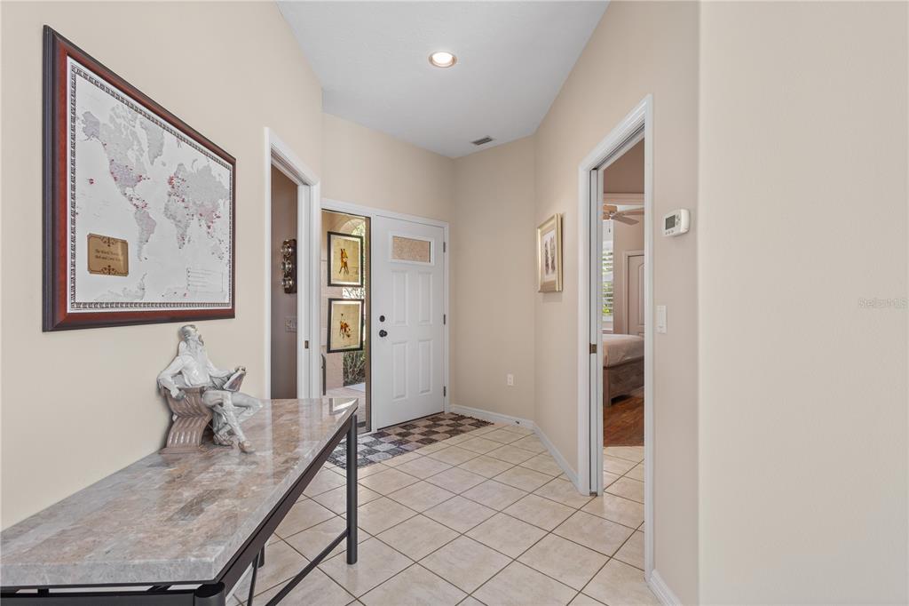 A tiled entryway features a console table, a world map, and a white front door — 7106 LA RONDA COURT, SARASOTA, FL