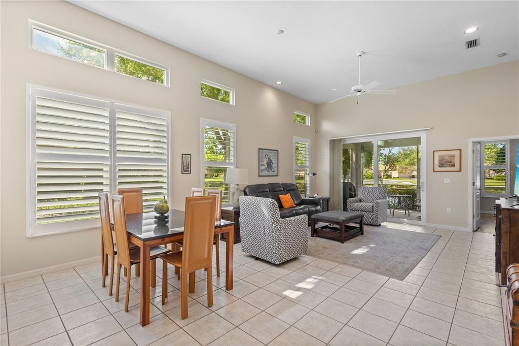 A bright open-concept living and dining area features tile floors, high ceilings, and large windows — 7106 LA RONDA COURT, SARASOTA, FL