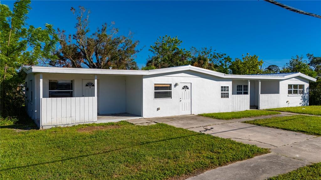A single-story white house with a flat roof, a concrete driveway, and a small porch — 4362 PINNACLE STREET, PUNTA GORDA, FL