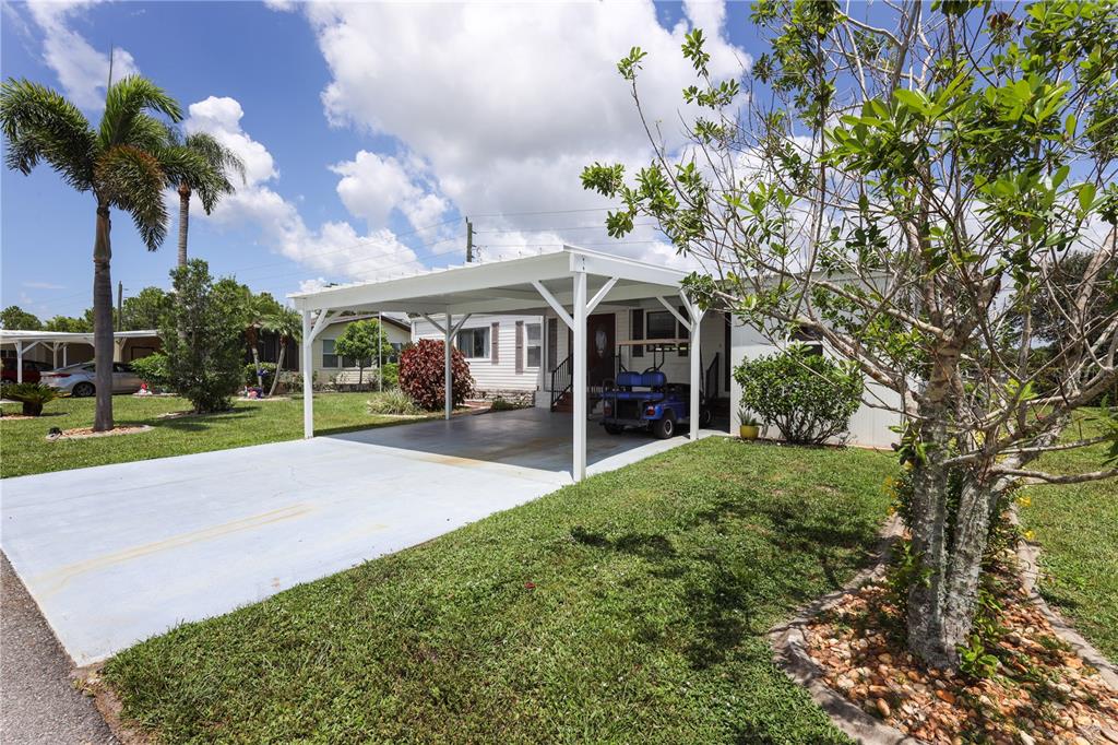 A white mobile home features a large carport and a golf cart parked in front — 2100 KINGS HIGHWAY UNIT 568, PORT CHARLOTTE, FL