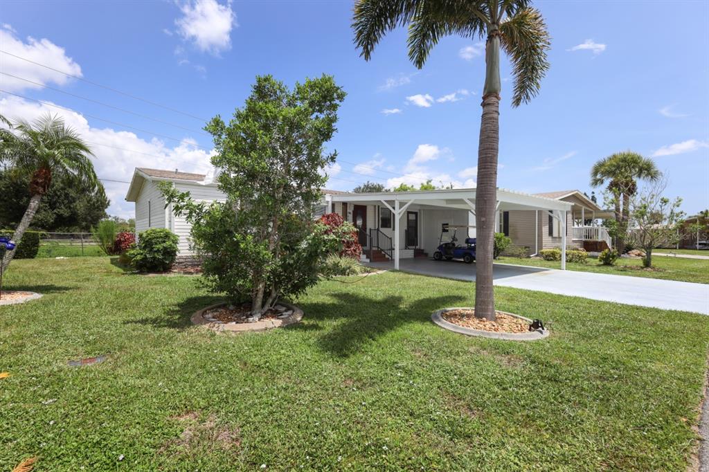 A single-story house with a carport, a golf cart, and palm trees on a lawn — 2100 KINGS HIGHWAY UNIT 568, PORT CHARLOTTE, FL