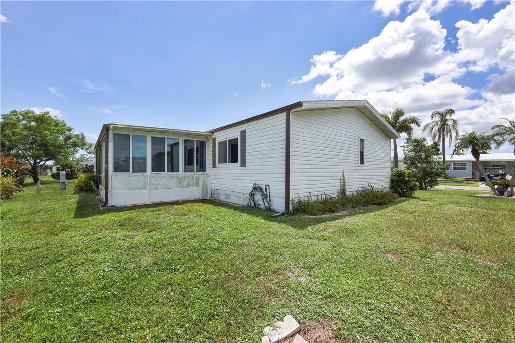 The exterior of a single-story manufactured home features white siding and an attached screened porch — 2100 KINGS HIGHWAY UNIT 568, PORT CHARLOTTE, FL