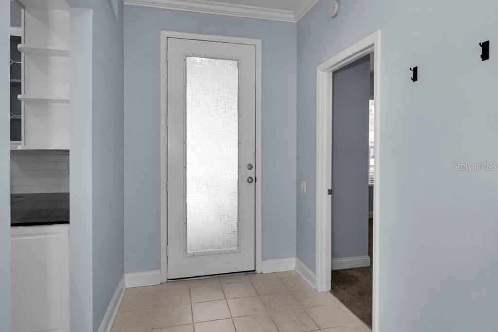 An entryway with light blue walls, tile flooring, a frosted glass door, and built-in shelving — 18104 HAMDEN PARK WAY, TAMPA, FL