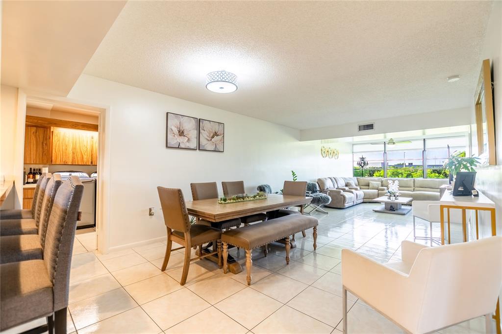An open-concept dining and living area features tile flooring, neutral walls, and large windows — 1508 WHITEHALL DRIVE UNIT 206, DAVIE, FL