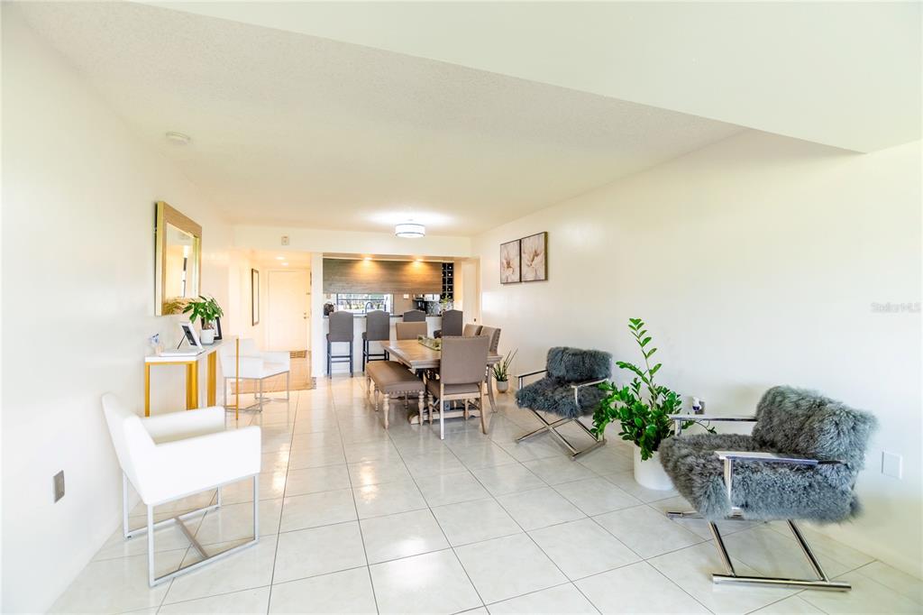 A bright, open-concept dining and living area features white tile floors and modern furniture — 1508 WHITEHALL DRIVE UNIT 206, DAVIE, FL