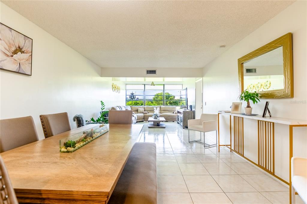 A dining area with a wooden table and bench leads into a bright living room — 1508 WHITEHALL DRIVE UNIT 206, DAVIE, FL