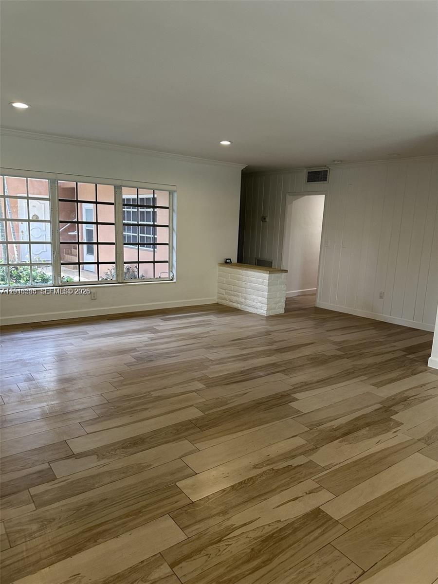 An empty room features light wood-look tile flooring, white walls, and a small brick partition — BAL HARBOUR, FL