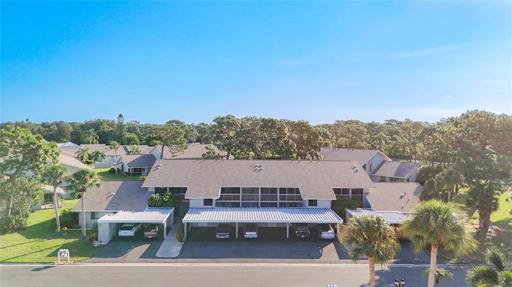 An aerial view of a two-story apartment building with covered parking spaces in front — 1407 PINE LAKE DRIVE UNIT 7, VENICE, FL