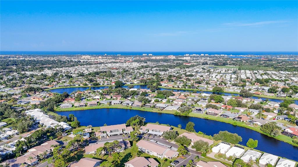 An aerial view shows a residential neighborhood with houses surrounding a large, winding lake — 1407 PINE LAKE DRIVE UNIT 7, VENICE, FL