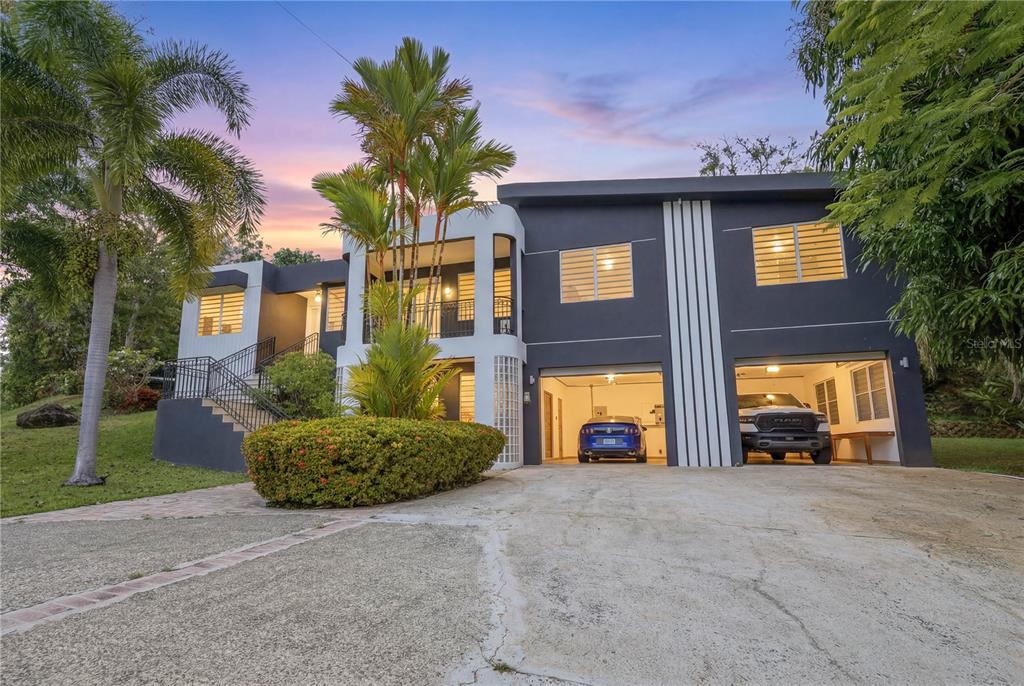 A two-story modern house with a two-car garage, palm trees, and an exterior staircase — 1 SECTOR LOS CRUZADOS, MAYAGUEZ, PR