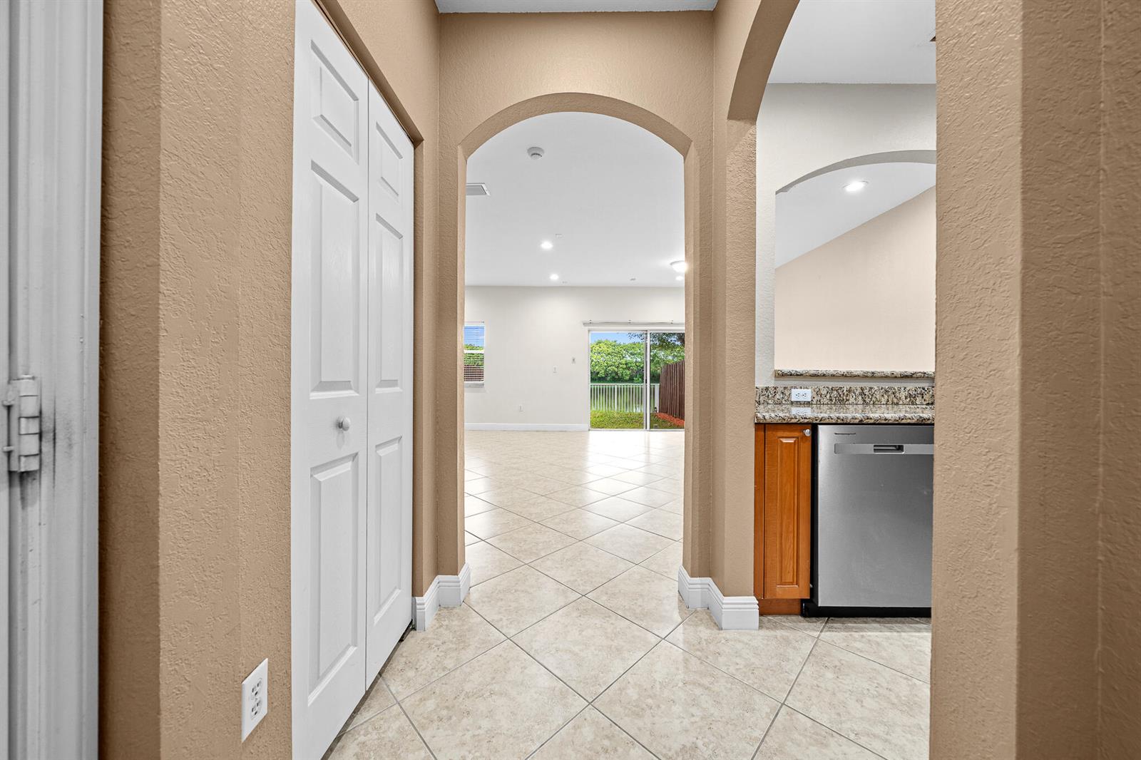 A tiled hallway leads through an arched doorway into an open living area with sliding doors — 5100 SW 141st Avenue, Miramar FL 33027, MIRAMAR, FL