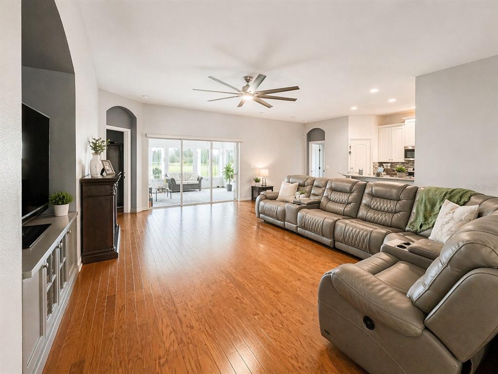 A living room with wood floors, a large sectional sofa, and sliding doors to a patio — 1314 EMERALD HILL WAY, VALRICO, FL