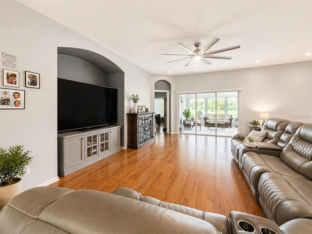 A living room features hardwood floors, a large television in an arched alcove, and sliding doors — 1314 EMERALD HILL WAY, VALRICO, FL
