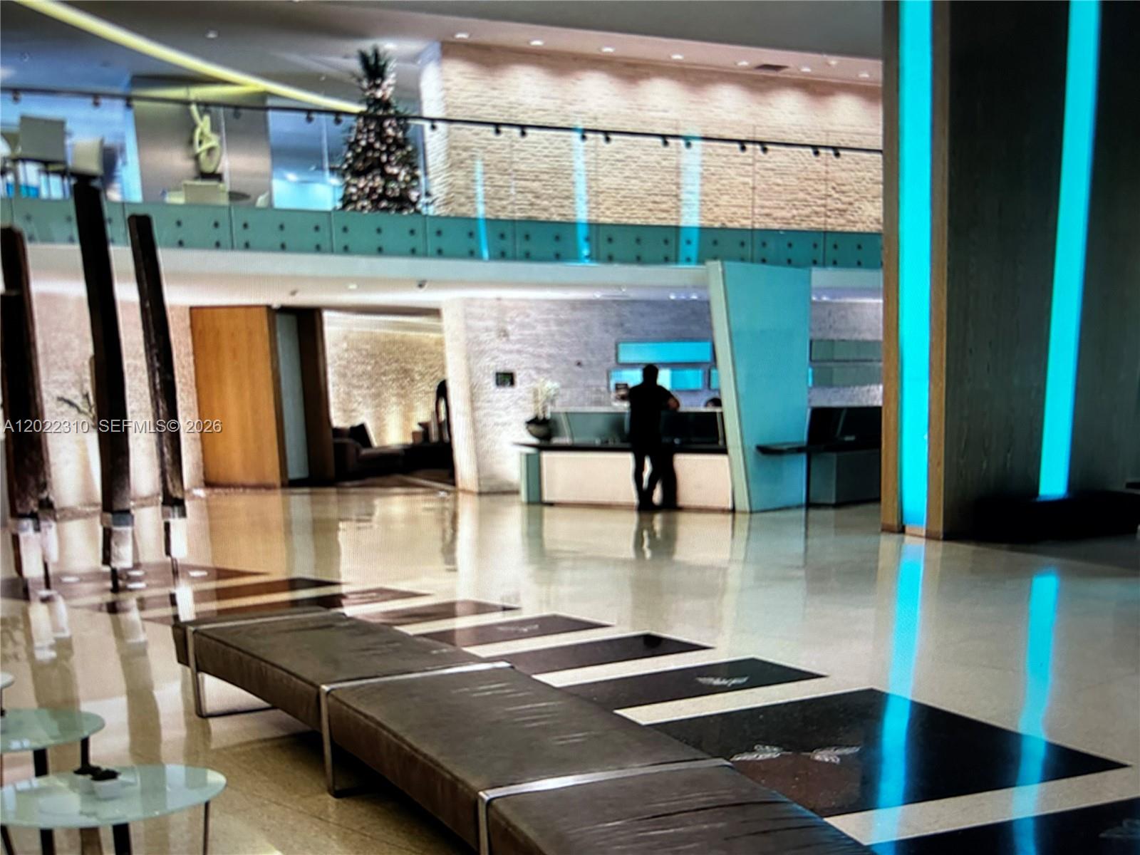 A modern building lobby features a reception desk, polished floors, and blue accent lighting — 92 SW 3rd St # 3703, Miami FL 33130, MIAMI, FL
