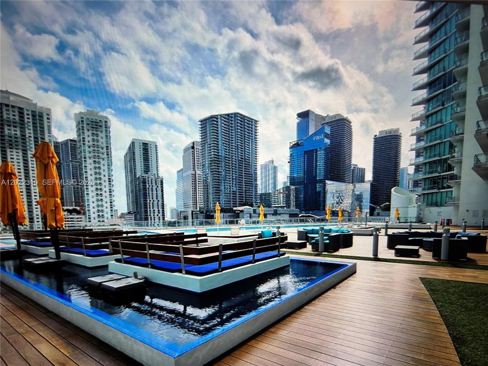 A rooftop pool deck features lounge seating, wooden decking, and views of a city skyline — 92 SW 3rd St # 3703, Miami FL 33130, MIAMI, FL