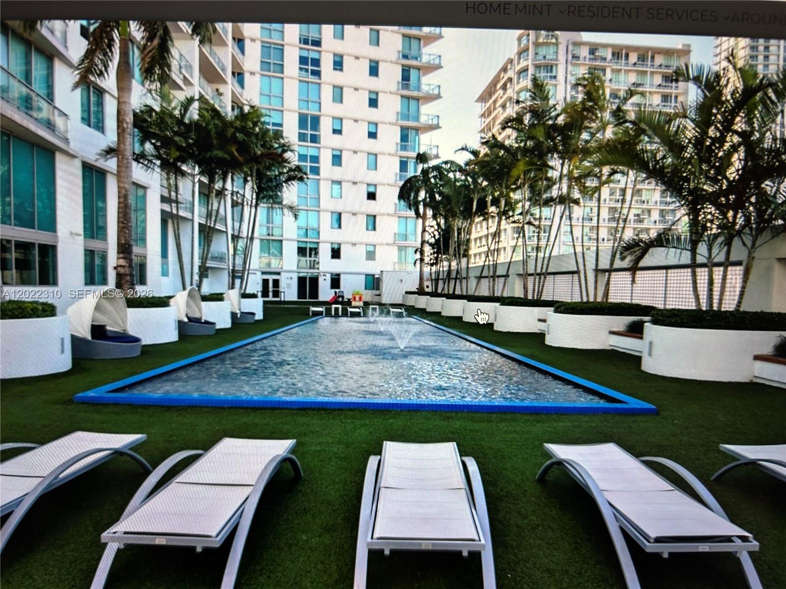 A rectangular swimming pool with fountains is surrounded by lounge chairs and palm trees — 92 SW 3rd St # 3703, Miami FL 33130, MIAMI, FL