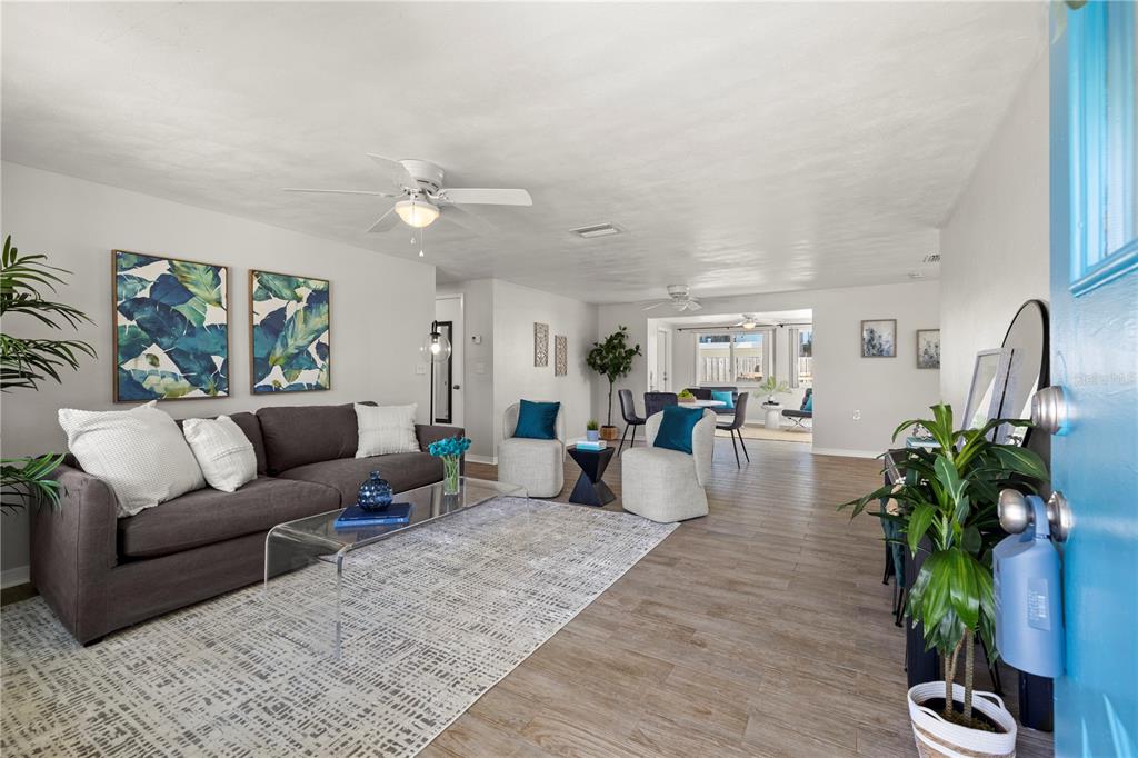 A living room features a gray sofa, two armchairs, a glass coffee table, and tile flooring — 5041 BAY BOULEVARD, PORT RICHEY, FL