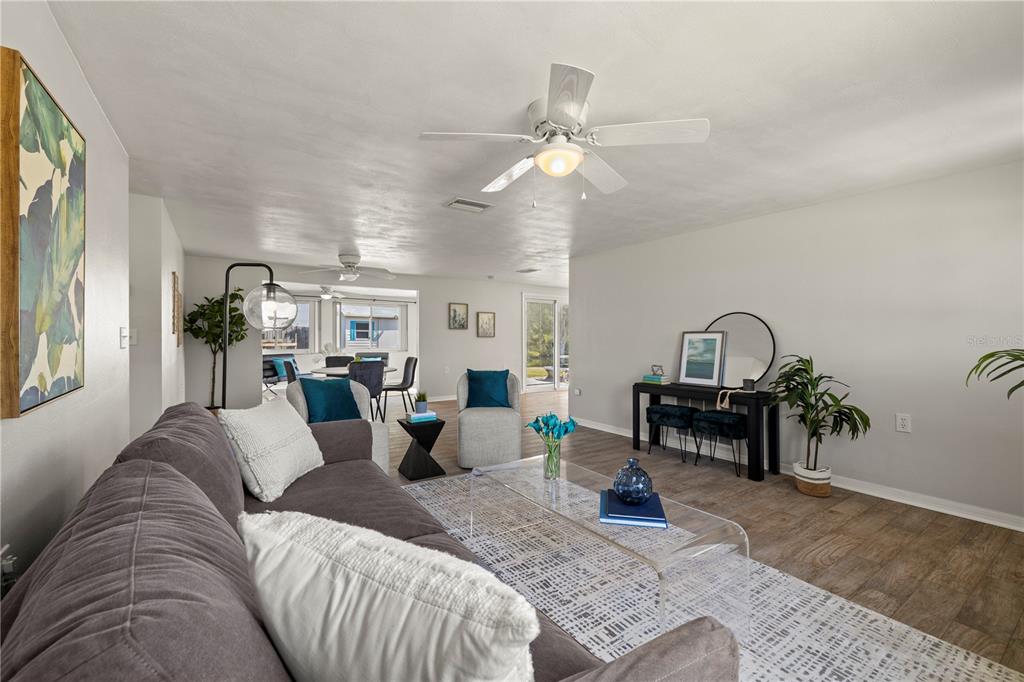 A living room features a gray sofa, a glass coffee table, and wood-look flooring — 5041 BAY BOULEVARD, PORT RICHEY, FL