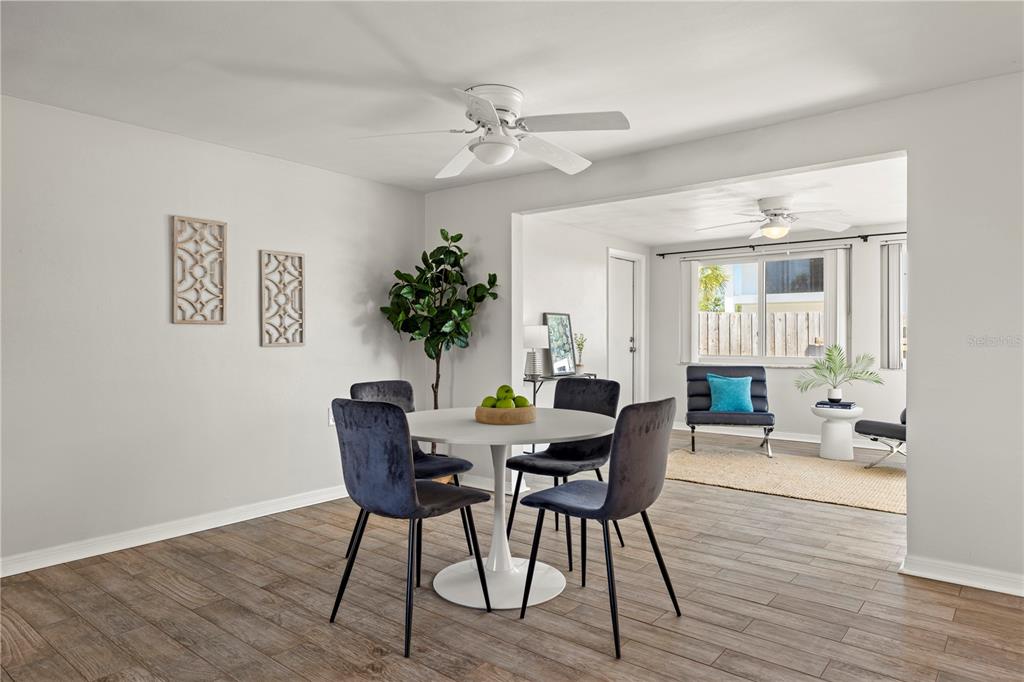A dining area with a round table and four chairs opens into a sunlit living space — 5041 BAY BOULEVARD, PORT RICHEY, FL
