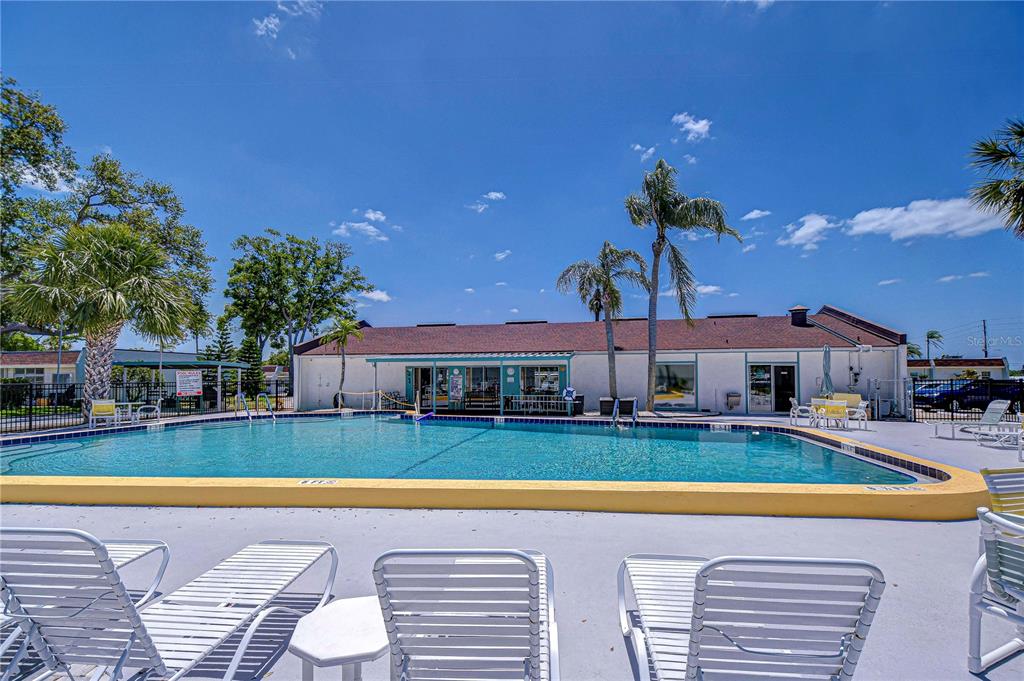 A swimming pool sits in front of a single-story building with a brown roof — 13870 OAKWOOD LANE, SEMINOLE, FL