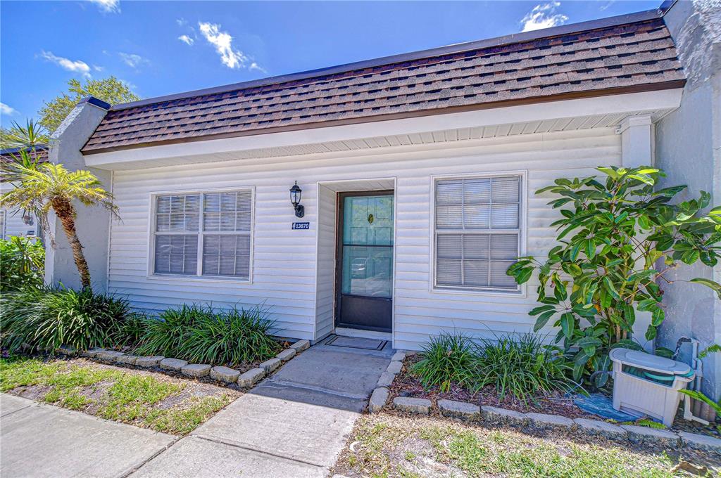 A single-story house with white siding, a shingled roof, and a front entrance — 13870 OAKWOOD LANE, SEMINOLE, FL