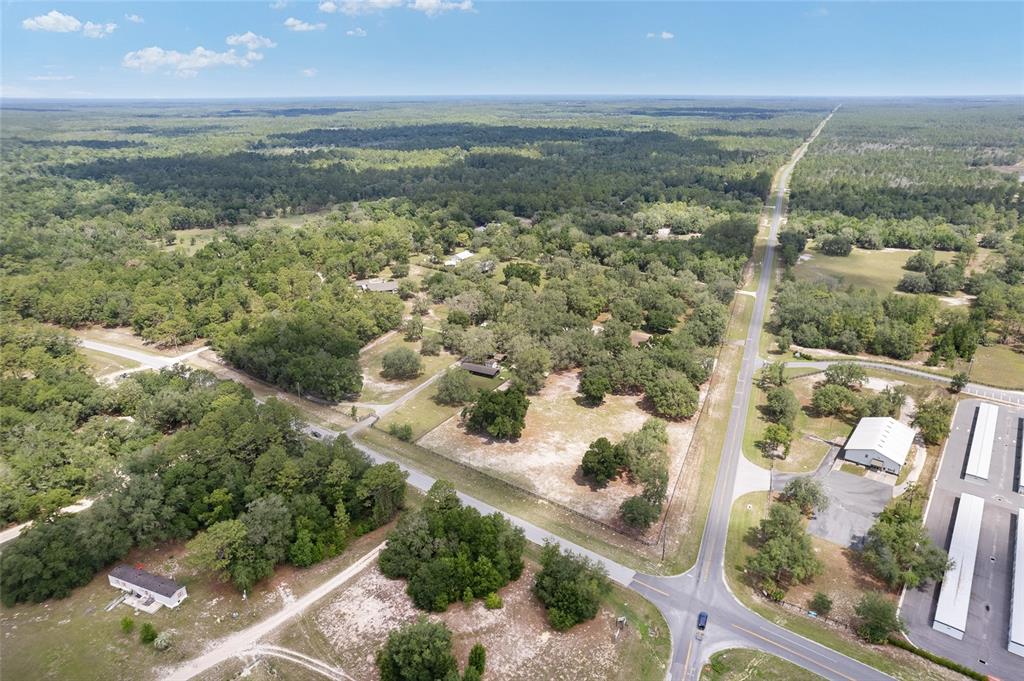 An aerial view shows a rural property with scattered trees, open land, and nearby roads — 10871 SE COUNTY ROAD 336, MORRISTON, FL