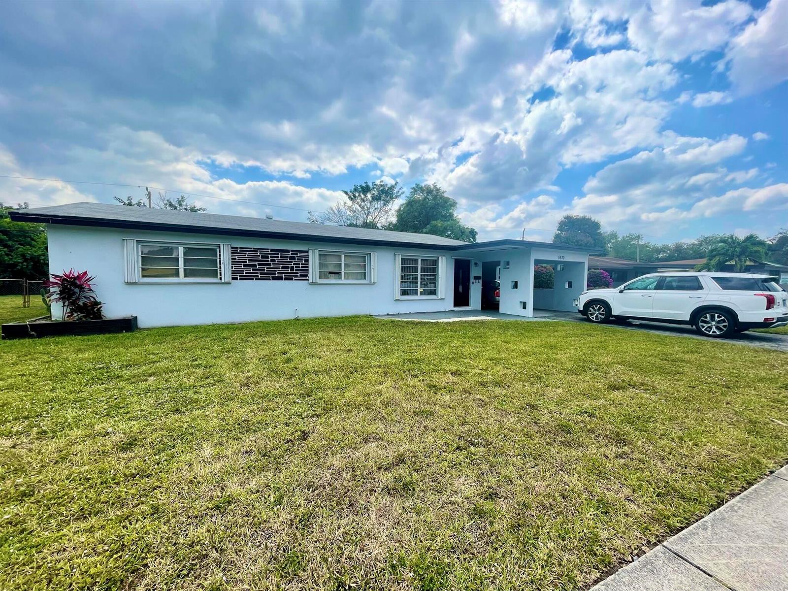 A single-story house with a light blue exterior, a front carport, and a grassy lawn — 5630 Hollywood Boulevard, Hollywood FL 33021, HOLLYWOOD, FL