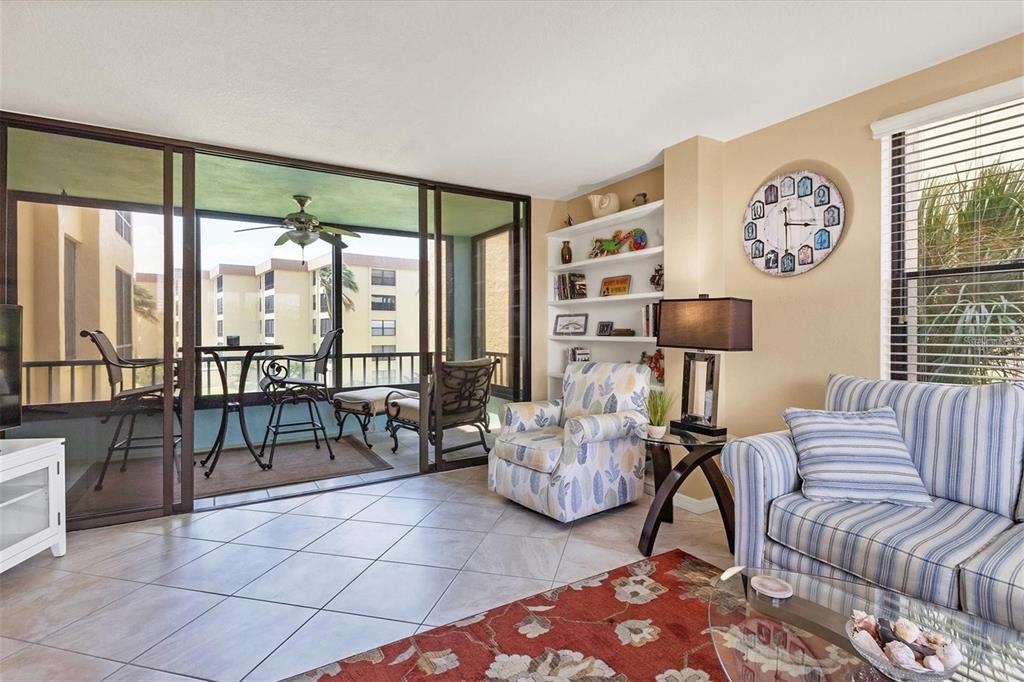 A living room features tile floors, a patterned armchair, a striped sofa, and a balcony view — 8776 MIDNIGHT PASS ROAD UNIT C307, SARASOTA, FL