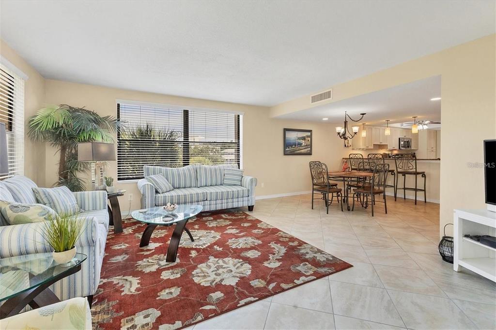 A living room and dining area with tile floors, a red floral rug, and striped furniture — 8776 MIDNIGHT PASS ROAD UNIT C307, SARASOTA, FL